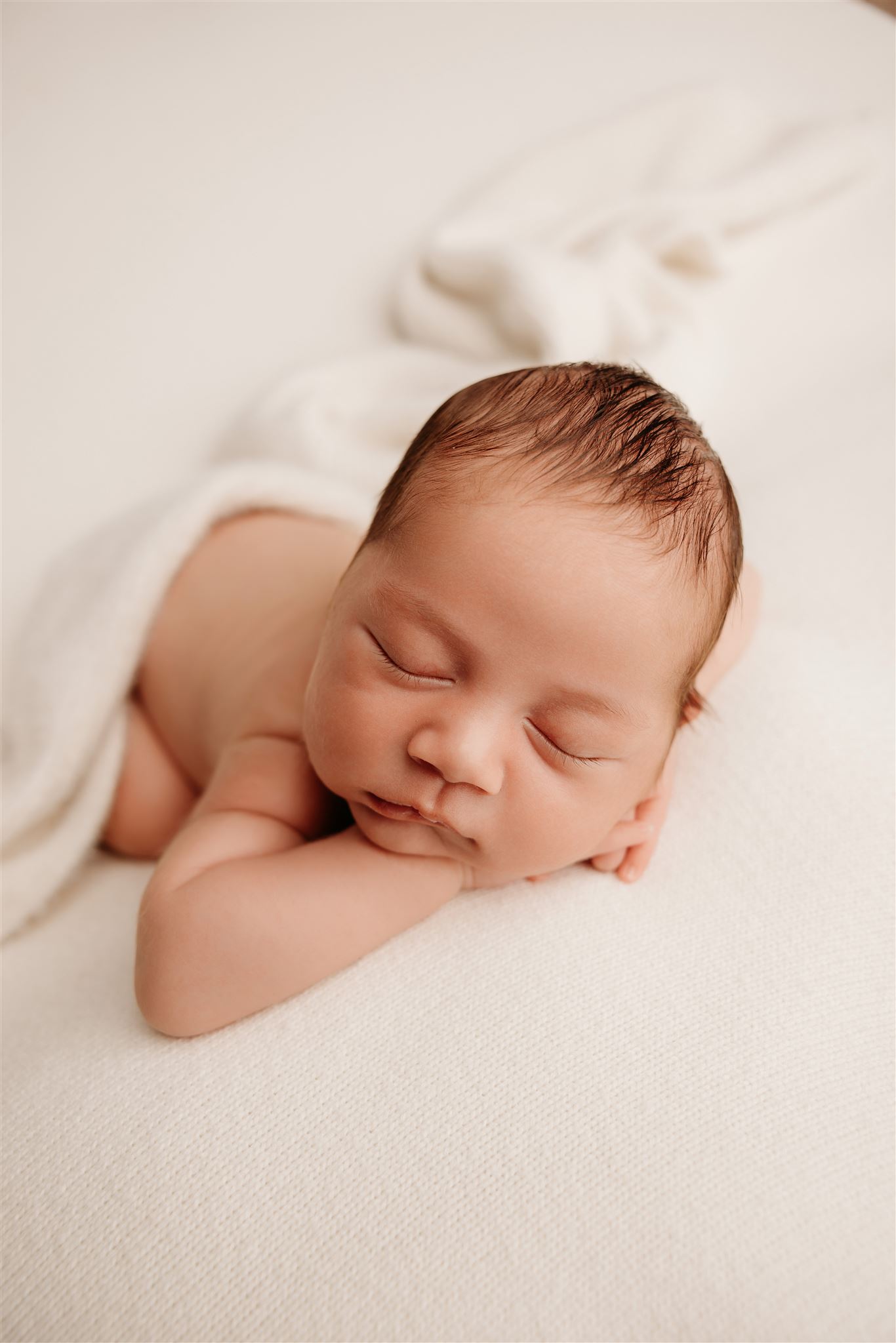 Elijah as a newborn baby posed on a cream backdrop bean bag during his newborn photoshoot in my auckland photography studio