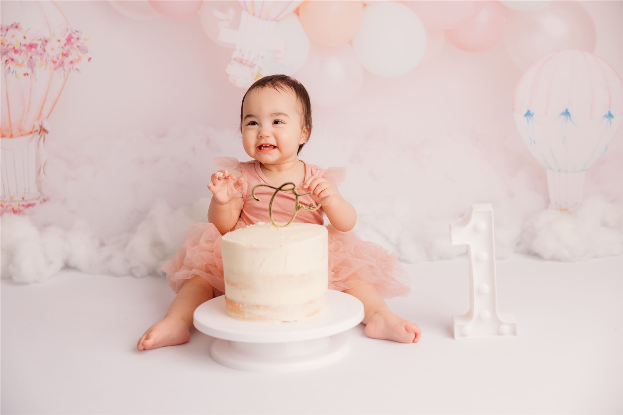 Ilenia sitting with her first birthday cake during her cakesmash photoshoot in auckland with michelle kelly photography