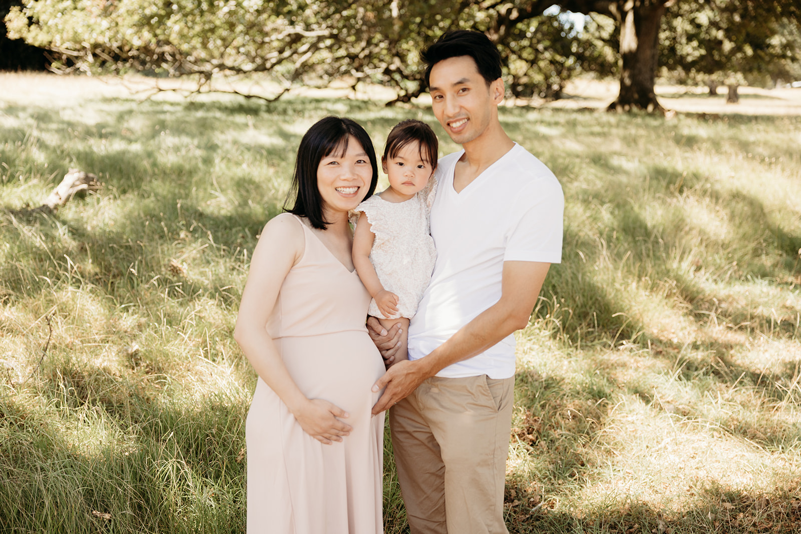 Karen and her husband and daughter holding one another during their family photoshoot with auckland photographer michelle kelly photography