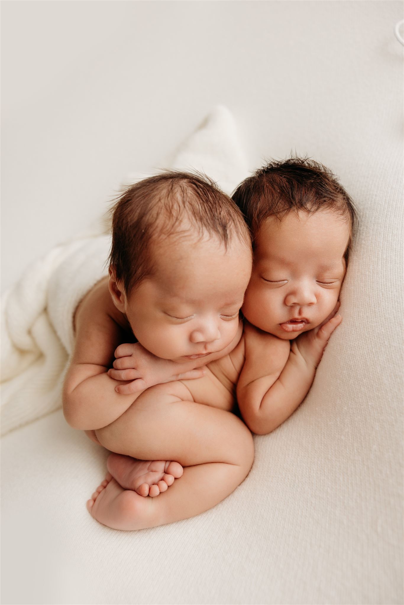 Marco and Marquez curled around one another sleeping during their newborn photoshoot with michelle kelly photography in auckland