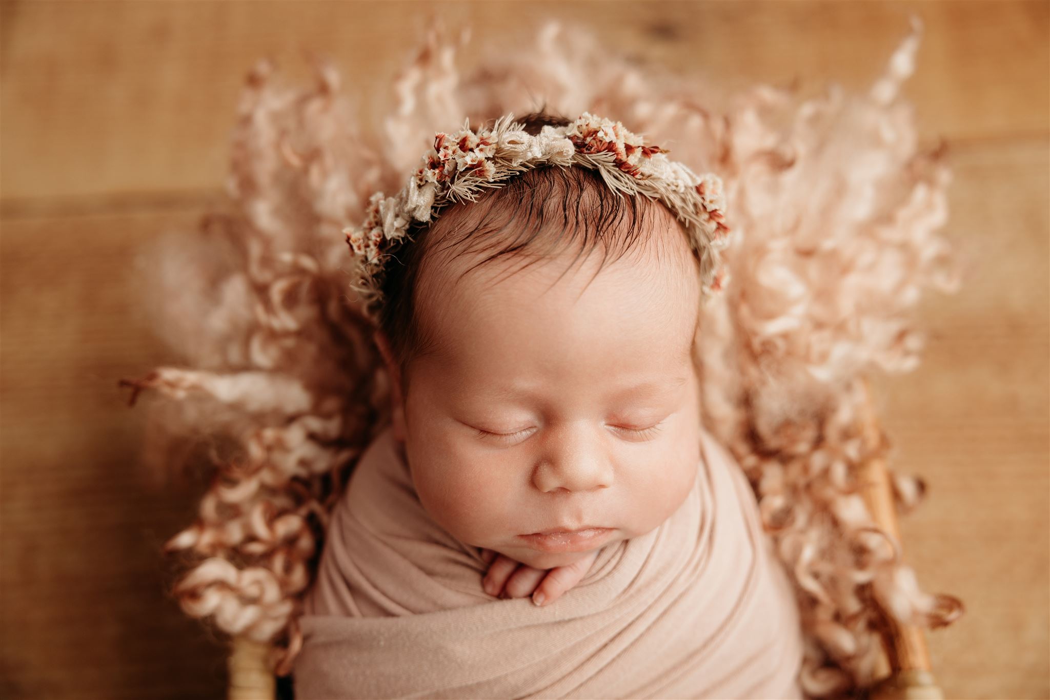 Baby Willow wearing a floral crown sitting in a basket sleeping while being photographed by Newborn studio photographer michelle kelly photography in auckland